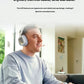 Lifestyle shot of a smiling player in a modern living room wearing the white ASTRO A30 while holding a controller, illustrating extended-wear comfort.