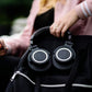 A woman holding Audio-Technica ATH-M50xENSO over-ear headphones resting on a black backpack — ideal for music lovers and professionals who need high-quality sound while commuting or traveling.