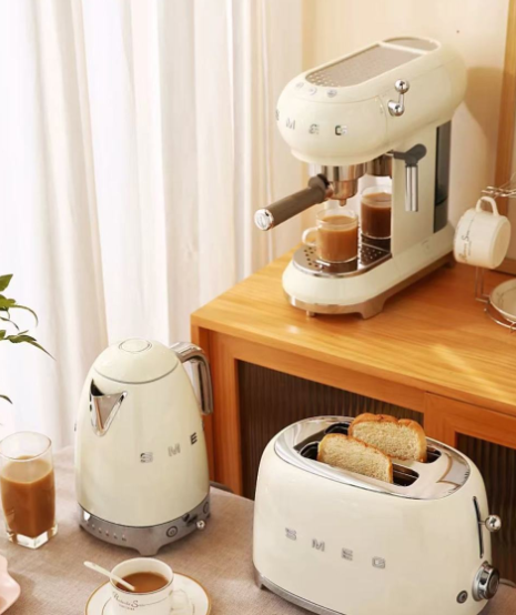 The complete Smeg 50's Style retro kitchen collection in cream, featuring the 4-slice toaster alongside the matching electric kettle and espresso coffee machine on a wooden countertop.