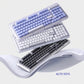 A promotional image showing all three colors of the Logitech Alto Keys K98M wireless keyboard—black, white, and blue—stacked together to highlight the UniCushion design.